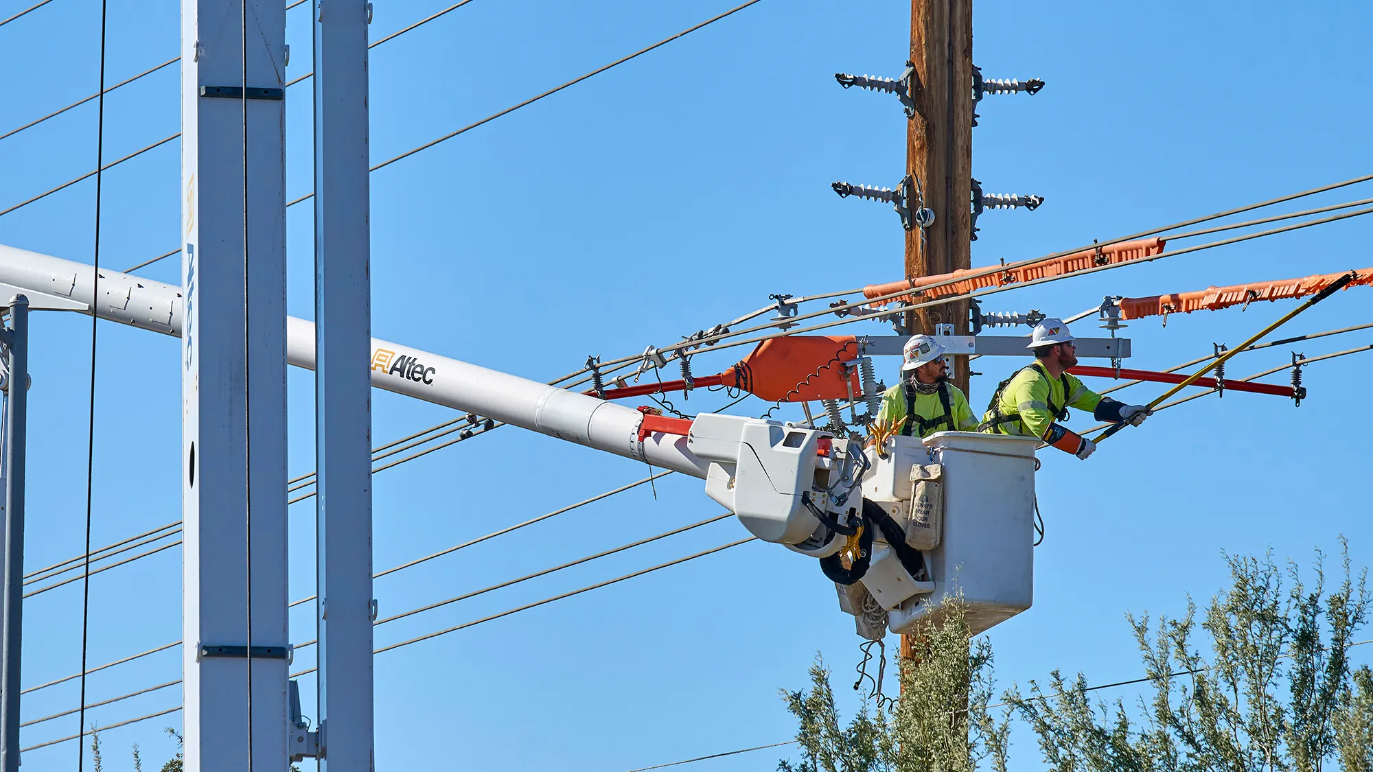 Two National Powerline worker working on an electrical pole from a crane.