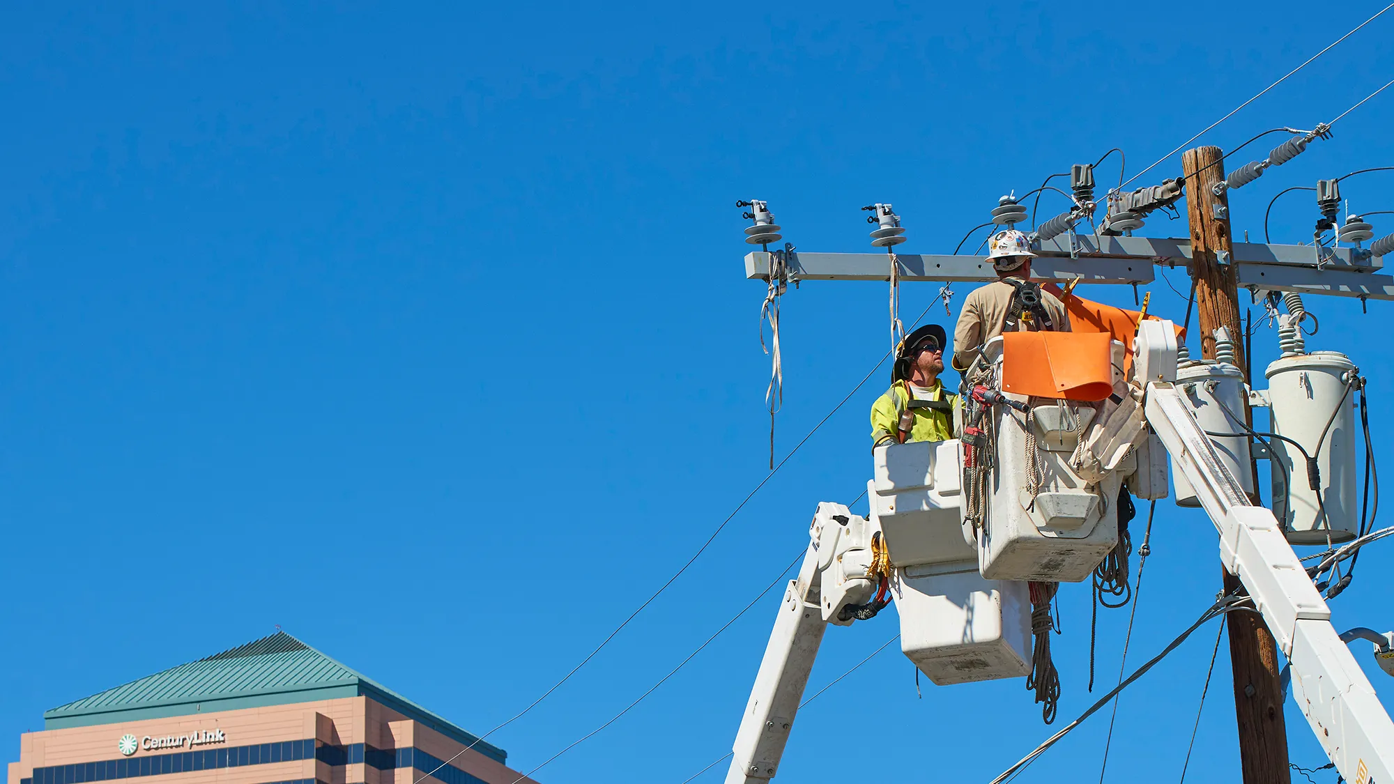 Two National Powerline workers looking at a powerline from a crane.